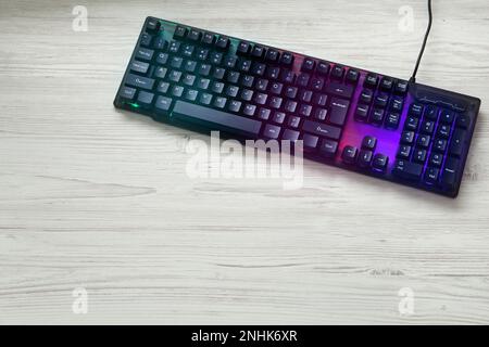 Modern RGB keyboard on white wooden table, top view. Space for text Stock Photo