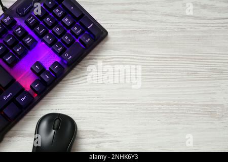 Modern RGB keyboard and mouse on white wooden table, flat lay. Space for text Stock Photo
