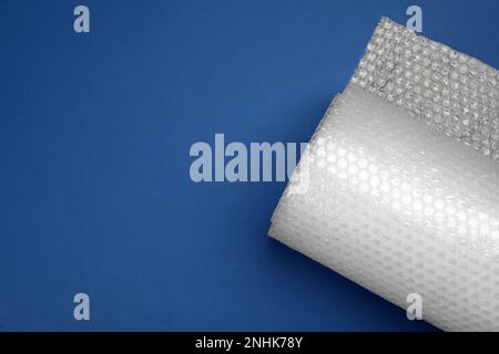 Bubble wrap roll on blue background, top view. Space for text Stock Photo