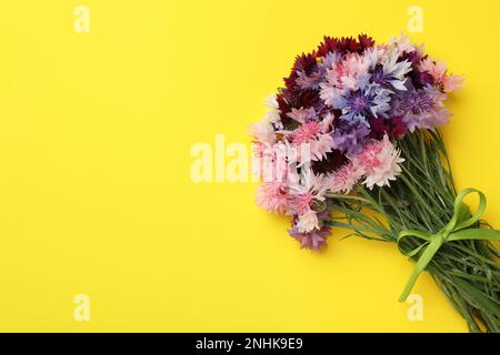 Bouquet of beautiful colorful cornflowers on yellow background, top view. Space for text Stock Photo