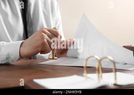 Male notary stamping document at table, closeup Stock Photo