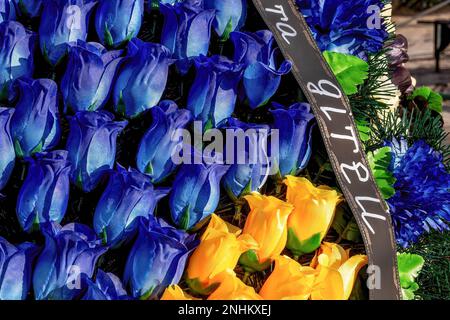 Kyiv, Kyiv Oblast, Ukraine. 21st Feb, 2023. Blue and yellow Ukrainian national colour flowers with a ribbon sign 'with children' lie on a grave of a soldier killed in combat against Russian forces, at the Lisove cemetery in the capital of Ukraine. As the full scale invasion of Ukraine by the Russian forces approaches its first anniversary the casualty rate is very hight, though the exact numbers are unknown. A minimum of 13 thousand Ukrainian soldiers have lost their lives. (Credit Image: © Dominika Zarzycka/SOPA Images via ZUMA Press Wire) EDITORIAL USAGE ONLY! Not for Commercial USAGE! Stock Photo