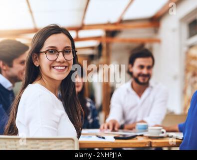 Glad to be part of our creative team. Portrait of a cheerful young creative businesswoman having a discussion with coworkers at a meeting around a Stock Photo