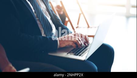 Taking notes. an unrecognizable businessman taking notes on his laptop during a meeting. Stock Photo