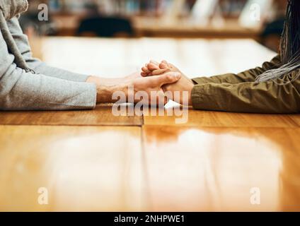 Im here for you. an unrecognizable university student consoling another student while sitting in the library. Stock Photo