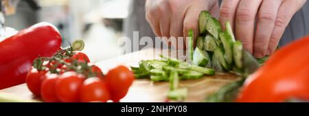 Green cucumbers are cut with knife in kitchen Stock Photo