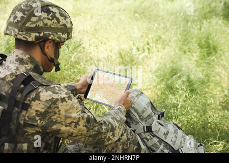 Soldier with backpack using tablet in forest Stock Photo