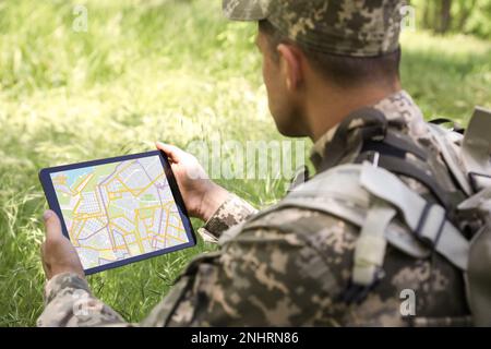 Soldier with backpack using tablet in forest Stock Photo