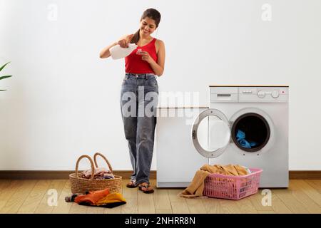 Happy young woman pouring detergent Stock Photo