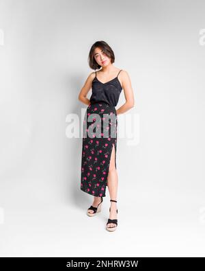 Full Body Beautiful Young Asian Woman in Long Floral Print Skirt and Black Silk Top Standing in Front of White Backdrop | Fas Stock Photo