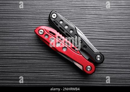 Modern compact portable multitool on black wooden table, top view Stock Photo