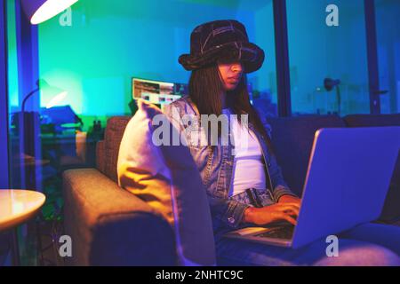 Programmer, hacker and woman typing on laptop in home at night in neon light to hack software. Cybersecurity, ransomware phishing and female coder Stock Photo