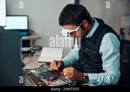 Technician, computer and engineer repair motherboard, microcircuit or electronic device in a workshop or shop. Person, man and guy fixing hardware Stock Photo
