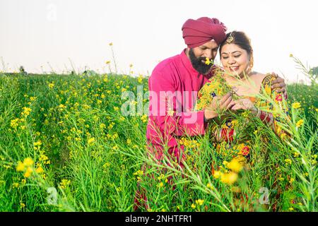 Happy young Punjabi sikh farmer couple standing together at agriculture field. Stock Photo