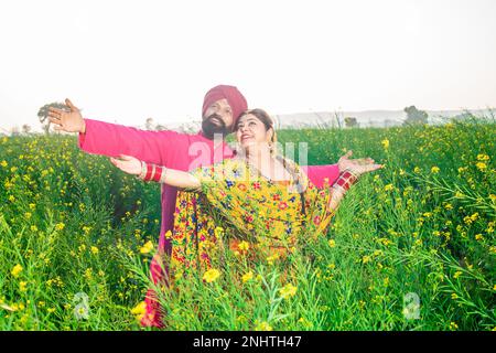 Happy young Punjabi sikh couple standing together at agriculture field. Stock Photo