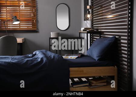 Wooden bed with soft silky bedclothes in room Stock Photo