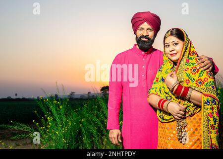 Portrait of Happy young Punjabi sikh farmer couple standing together at agriculture field. copy space. Stock Photo