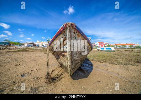 Old wooden fishing boat docked in low tide sand. Cabanas de Tavira, Portugal Stock Photo