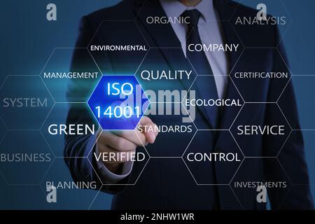 Businessman pointing at virtual icon with text ISO 14001 on color background, closeup Stock Photo