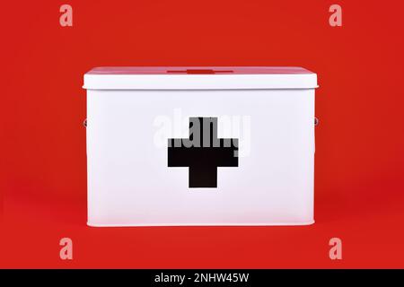 White first aid kit with black cross on red background Stock Photo