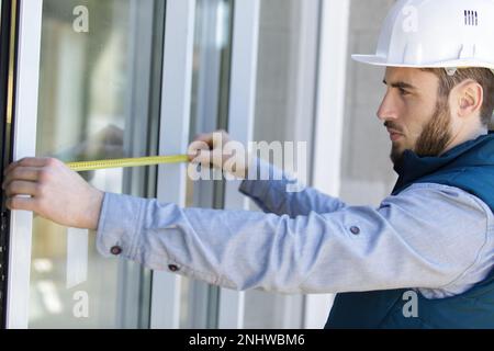 concentrated male builder measuring a window Stock Photo