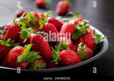 Strawberries in a black plate on dark background. Stock Photo