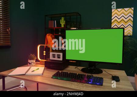 Modern computer and RGB keyboard on wooden table indoors. Mockup green screen Stock Photo