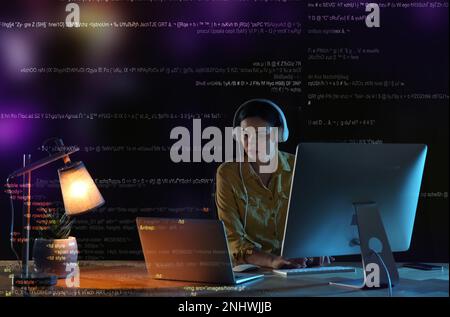 Programmer with headphones working in office at night Stock Photo