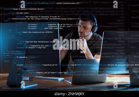 Programmer with headphones working in office at night Stock Photo
