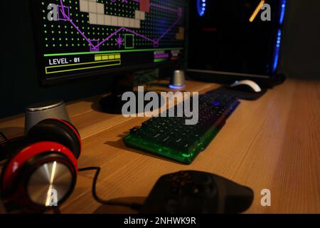 RGB keyboard, modern computer and headphones on wooden table indoors Stock Photo