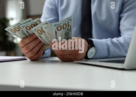 Cashier counting money at desk in bank, closeup