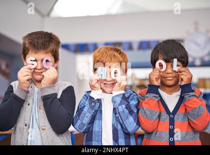 Holding up their favourite letters. elementary school children in class. Stock Photo