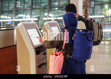 A couple checking-in flights using a smartphone at a self-check-in kiosk at the airport Stock Photo
