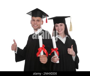 Happy students in academic dresses with diplomas on white background Stock Photo