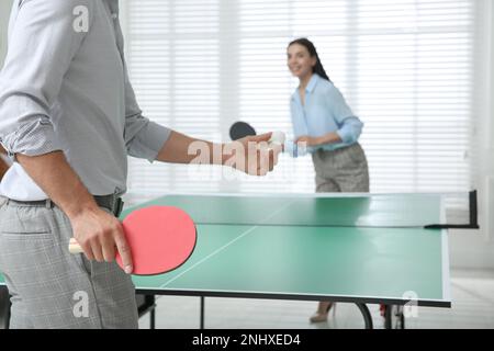 Business people playing ping pong in office, focus on tennis racket Stock Photo