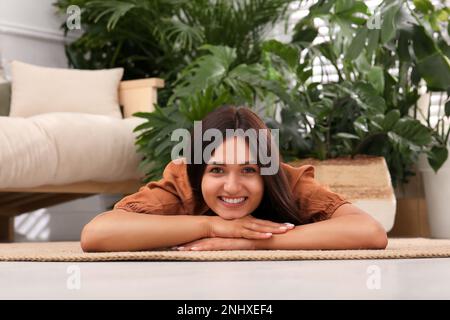 Beautiful woman lying on floor in living room decorated with houseplants. Interior design Stock Photo