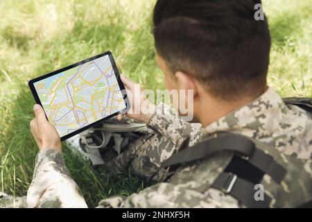 Soldier with backpack using tablet in forest Stock Photo