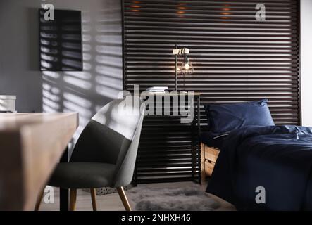 Wooden bed with soft silky bedclothes in room Stock Photo