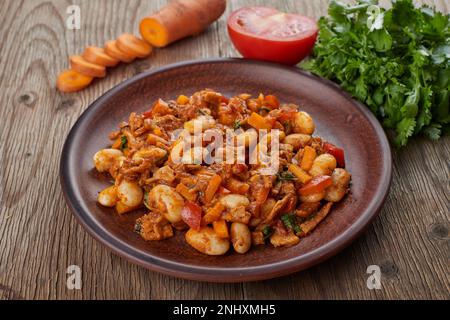 stewed beans with vegetables and herbs in a plate, on a wooden background Stock Photo