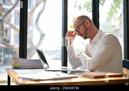 Professional and focused Caucasian businessman or male boss pensively thinking about his project, making serious decisions, planning project, working Stock Photo