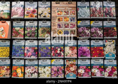 Neat rows of colourful Johnsons flower seed packets hanging on display stand in UK garden centre. Stock Photo