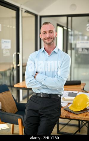 Portrait, Successful and confident Caucasian male engineer or architect stands with arms crossed in the engineer's office. Stock Photo