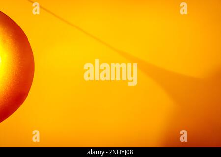 Abstract background of hanging pendant lamp with shiny surface casting shadow on surface Stock Photo