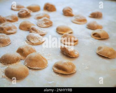 Closeup process making tortelli stuffed with pumpkin filling homemade pasta, grandma cook seasonal 'tortelli di zucca', traditional italian filled pas Stock Photo