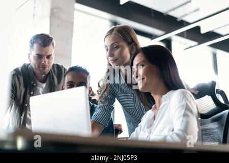 Friendly creative diverse colleagues team discuss online project use computer at workplace Stock Photo