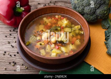 vegetable soup with vegetables and cauliflower in a clay plate, on a wooden surface Stock Photo
