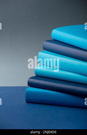 Stack of books Different tones of blue, on desk, with gray background Stock Photo