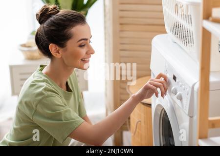 Positive young woman switching washing machine at home,stock image Stock Photo