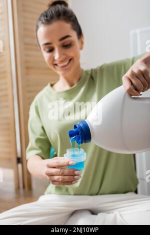 Smiling woman pouring liquid washing powder in laundry room,stock image Stock Photo