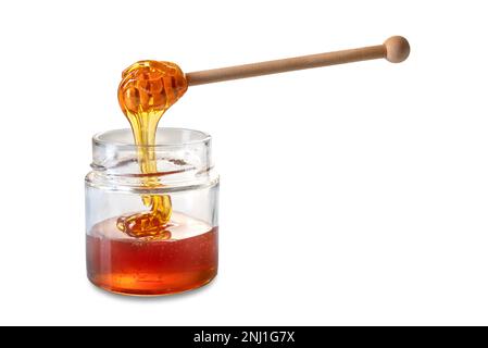 Honey dripping from wooden honey dipper in glass jar, chestnut honey with amber color, isolated on white with clipping path Stock Photo